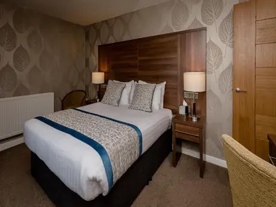 a hotel room with a large bed and a desk at The Melbreak Hotel in Great Clifton
