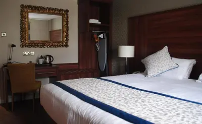 a bedroom with a bed and a desk and a mirror at The Melbreak Hotel in Great Clifton