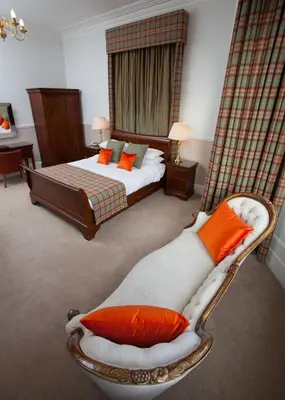 a bedroom with a bed and a chair with orange pillows at Cressfield Country House Hotel in Ecclefechan