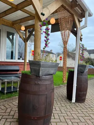 a wooden pergola with two large barrels with plants in it at Lynebank House Hotel, Bed & Breakfast in Carlisle