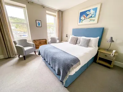 a bedroom with a blue bed and a chair at Sail Lofts in Douglas