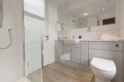 a white bathroom with a toilet and a glass shower at Sail Lofts in Douglas
