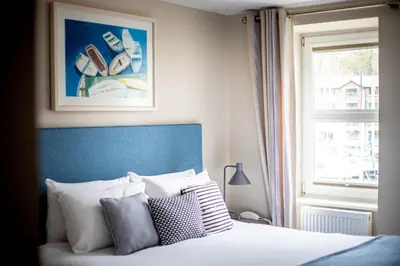 a bedroom with a bed with a blue headboard and a window at Sail Lofts in Douglas