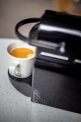 a cup of coffee sitting on top of a coffee machine at Sail Lofts in Douglas