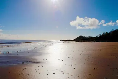a beach with the sun shining on the sand at Lapwing, Skylark & Curlew Seaside Chalets in Kirkbean