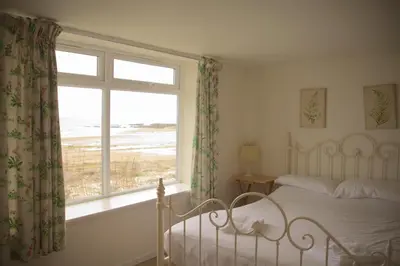 a bedroom with a bed and a window with a view of the ocean at Shore Cottage in Dumfries