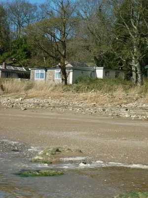a house on the side of a road next to a river at Shore Cottage in Dumfries