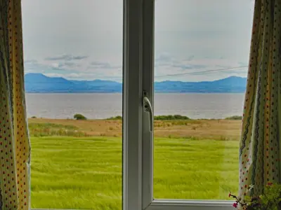 a window with a view of a field of grass at Powillimount Cottage in Kirkbean