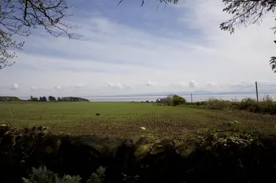 a green field with the ocean in the background at West Lodge in Kirkbean