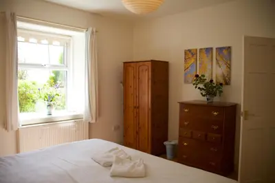 a bedroom with a bed and a window and a dresser at West Lodge in Kirkbean