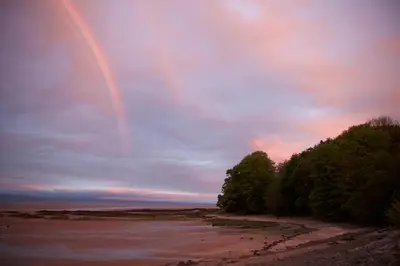 a rainbow in the sky over a beach at West Lodge in Kirkbean