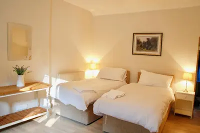 two beds in a small room with two lamps at Little Dunbar Cottage in Kirkbean