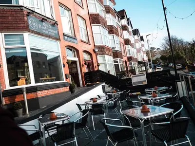 a patio with tables and chairs in front of a building at Glen Mona in Douglas