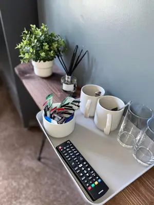 a tray with a remote control and cups on a table at Hall Park Hotel self check in in Workington