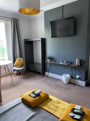 a living room with a bed and a tv at Hall Park Hotel self check in in Workington