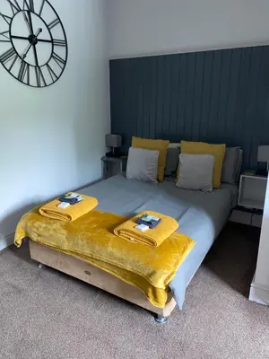 a bedroom with a large bed with a clock on the wall at Hall Park Hotel self check in in Workington