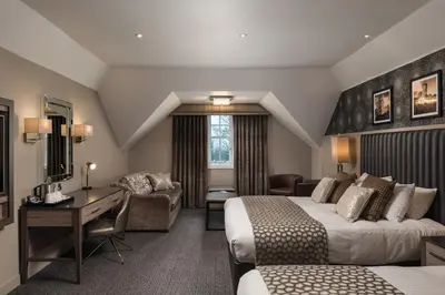 a hotel room with two beds and a desk at Hetland Hall Hotel in Dumfries