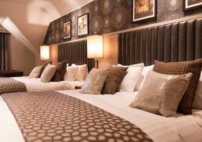 a row of four beds in a hotel room at Hetland Hall Hotel in Dumfries