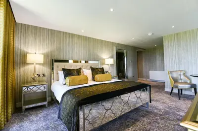 a bedroom with a large bed and a chair at Hetland Hall Hotel in Dumfries