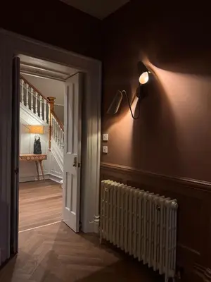 a hallway with a lamp on the wall and a staircase at Lyzzick in Keswick