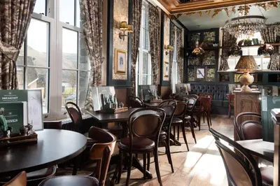 a restaurant with tables and chairs and windows at The Ullswater Inn- The Inn Collection Group in Glenridding