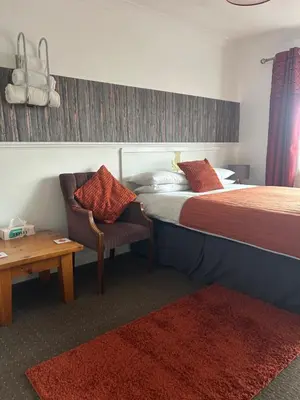 a bedroom with a bed and a chair and a table at The Thistle in Stranraer