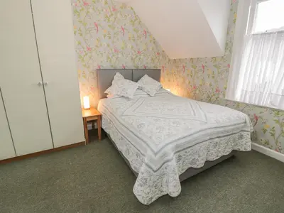 a bedroom with a bed with a floral wallpaper at 27-29 St Marys Place in Kirkcudbright