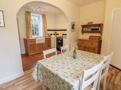 a dining room with a table and a kitchen at 27-29 St Marys Place in Kirkcudbright