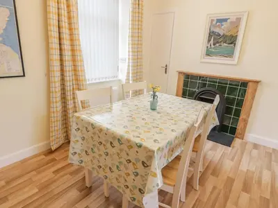 a dining room with a table and chairs and a fireplace at 27-29 St Marys Place in Kirkcudbright