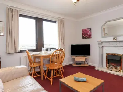 a living room with a table and a tv at Harbour Side in Maryport