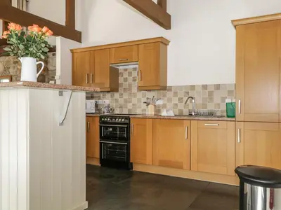 a kitchen with wooden cabinets and a black stove top oven at Buttermere in Cockermouth