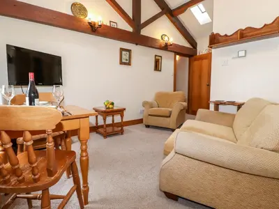 a living room with a table and chairs and a flat screen tv at The Hayloft in Keswick