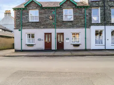 a brick house with red doors on a street at Swinside Cottage in Keswick