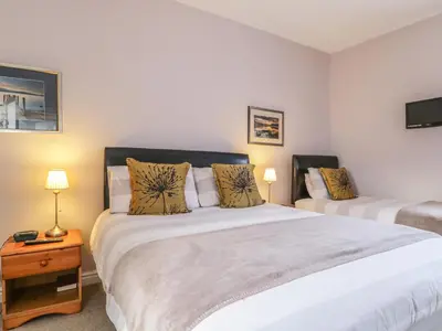 a bedroom with a large bed and a night stand at Swinside Cottage in Keswick