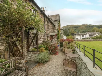 a stone house with a table and chairs outside at Tanner Croft Cottage in Ambleside