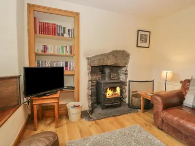 a living room with a fireplace and a television at Tanner Croft Cottage in Ambleside