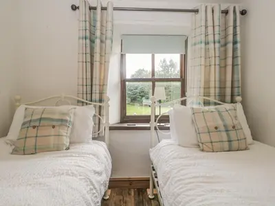 two beds in a room with a window at Tanner Croft Cottage in Ambleside