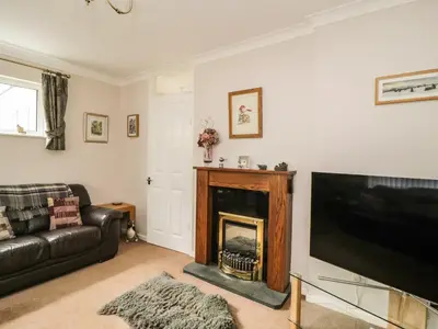 a living room with a fireplace and a television at Manesty View in Keswick