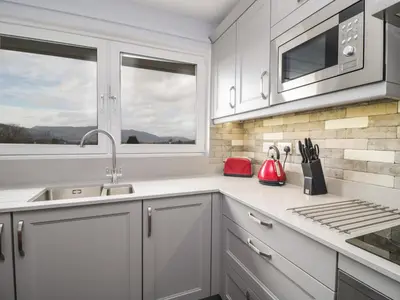 a kitchen with white cabinets and a sink and a window at Manesty View in Keswick