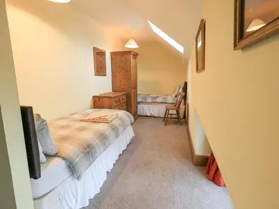 a bedroom with a bed and a chair in it at Tithe Cottage in Cockermouth