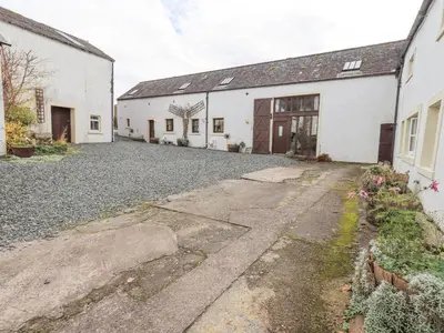 an empty driveway in front of two white buildings at Tithe Cottage in Cockermouth