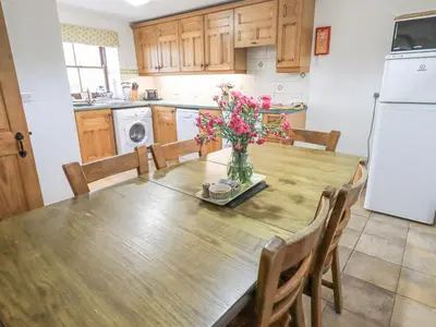a kitchen with a table with a vase of flowers on it at Tithe Cottage in Cockermouth
