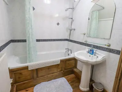 a bathroom with a tub and a sink and a mirror at The Byre in Cockermouth
