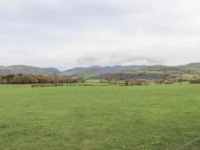 a large green field with mountains in the background at The Byre in Cockermouth