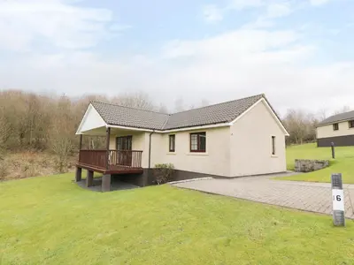 a white house with a deck on a yard at Savita Cottage in Girvan
