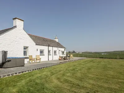 a white building with a patio and a grass field at Longforth Farm Cottage in Gillespie