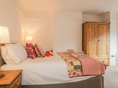 a bedroom with a bed and a wooden cabinet at Roselea in Keswick