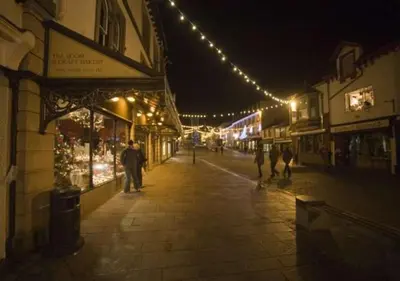a man walking down a street at night with lights at Lyndhurst in Keswick