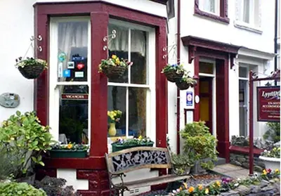 a bench in front of a building with flowers at Lyndhurst in Keswick