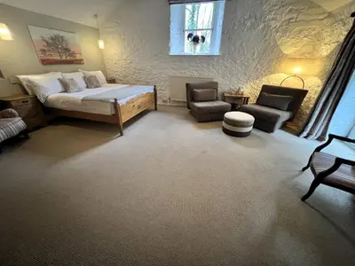 a bedroom with a bed and a couch and a chair at Ravenstone Lodge Country House Hotel in Keswick